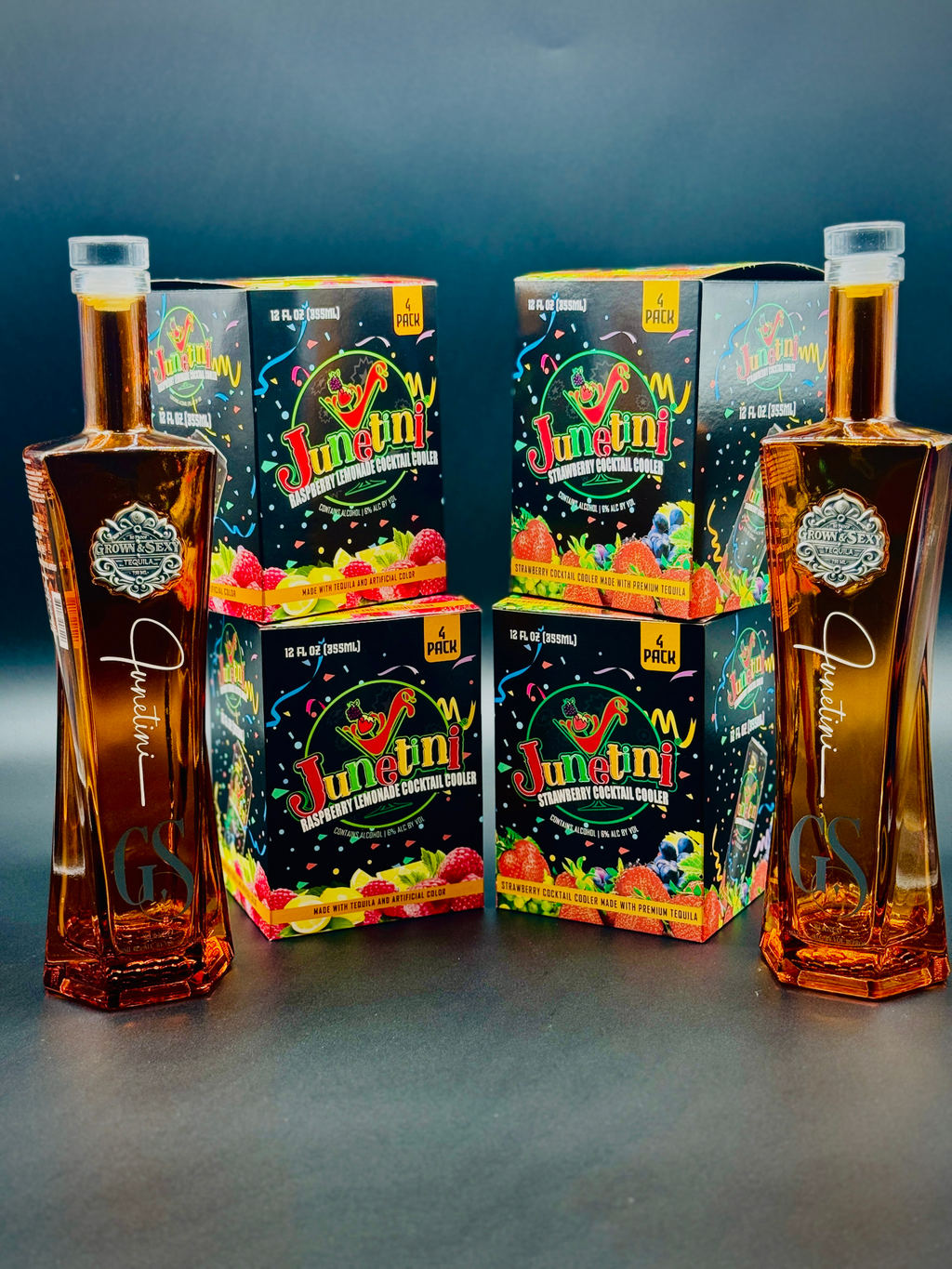 Two bottles of Grown & Sexy tequila with boxes of Junetini Raspberry Lemonade and Strawberry Cocktail Coolers on a dark background